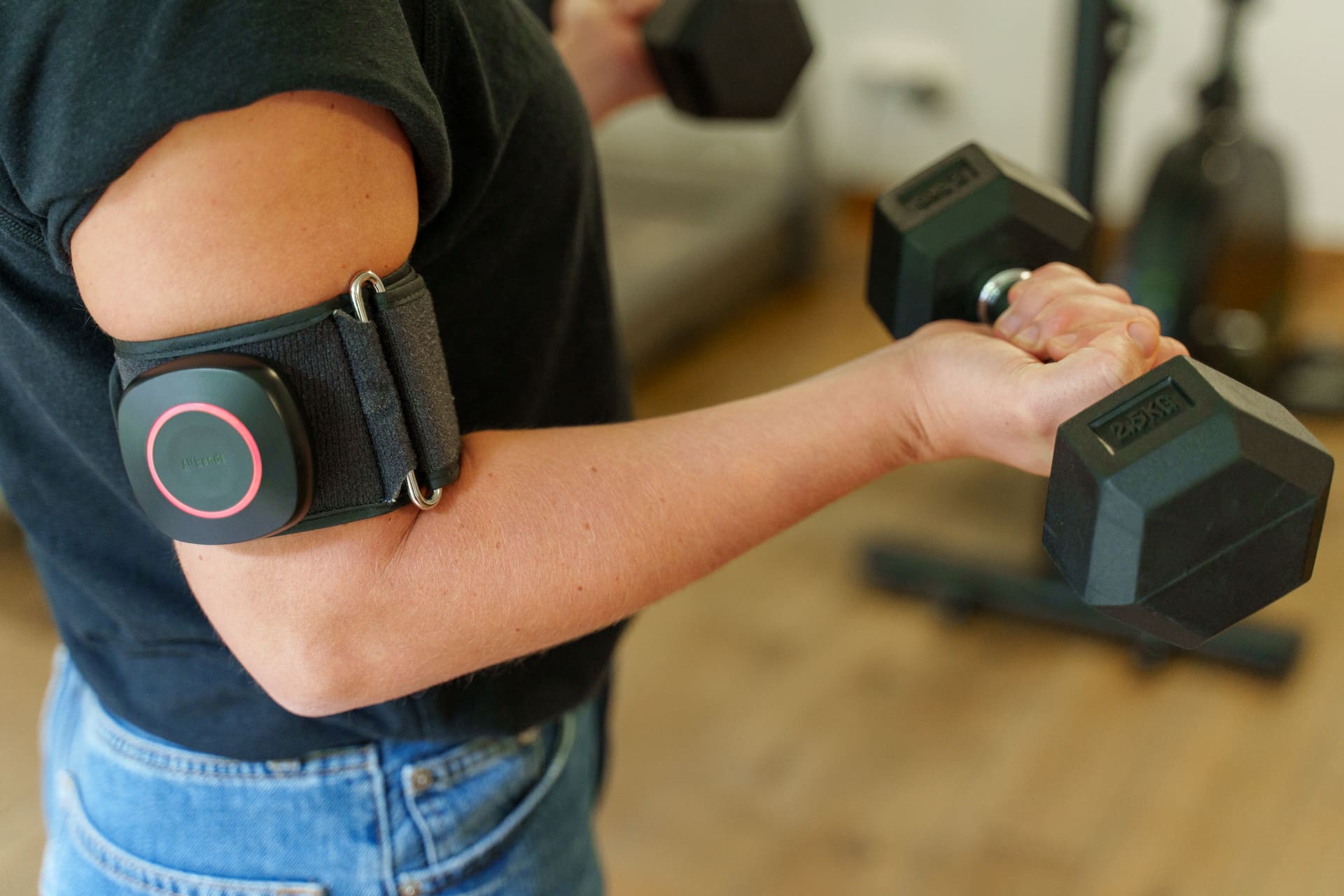 Patiënt voert een lichte bicepsoefening met een dumbbell uit, met de BFR-cuff rond de bovenarm