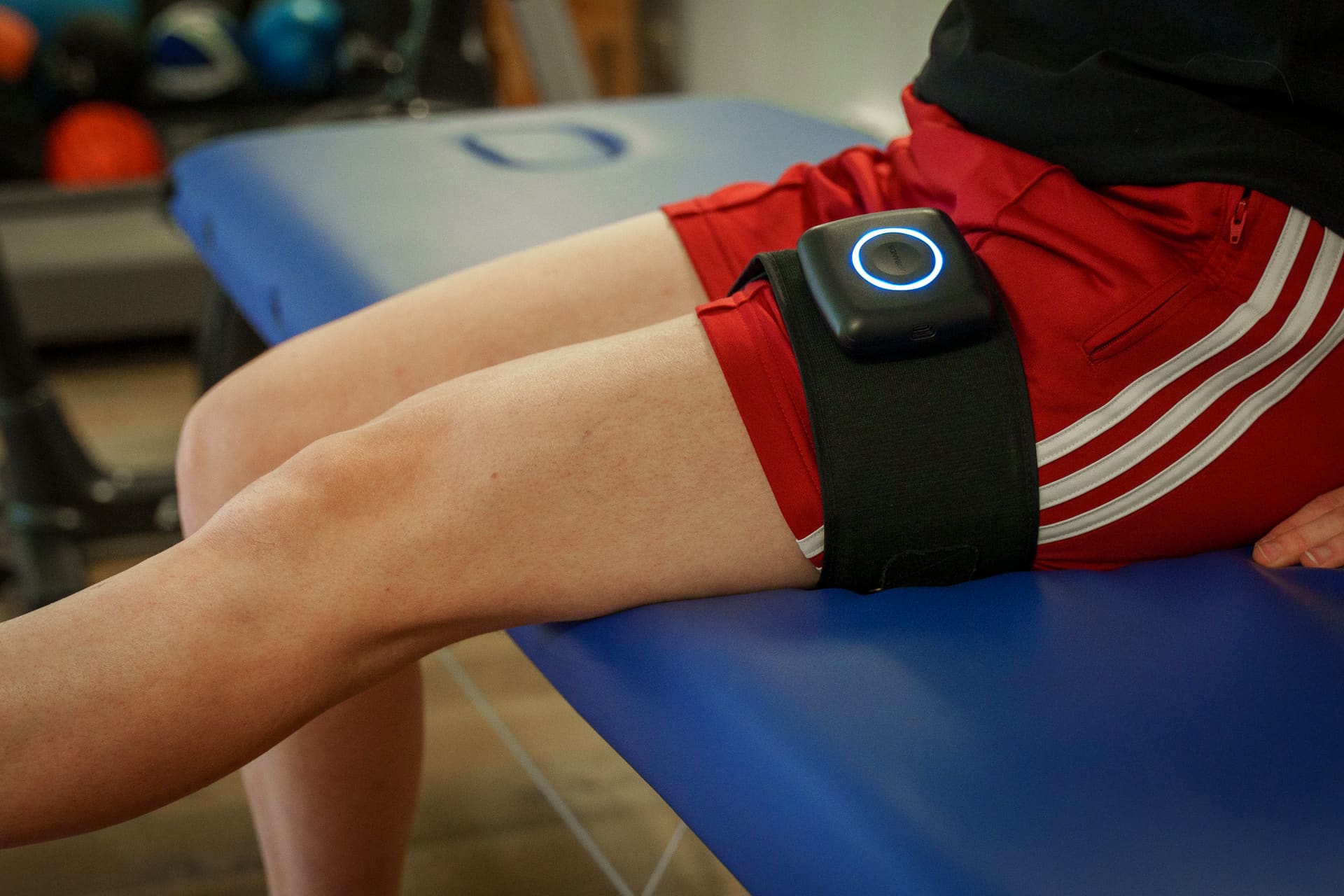 Close-up van een blood flow restriction-cuff rond het bovenbeen, met het toestel duidelijk in beeld