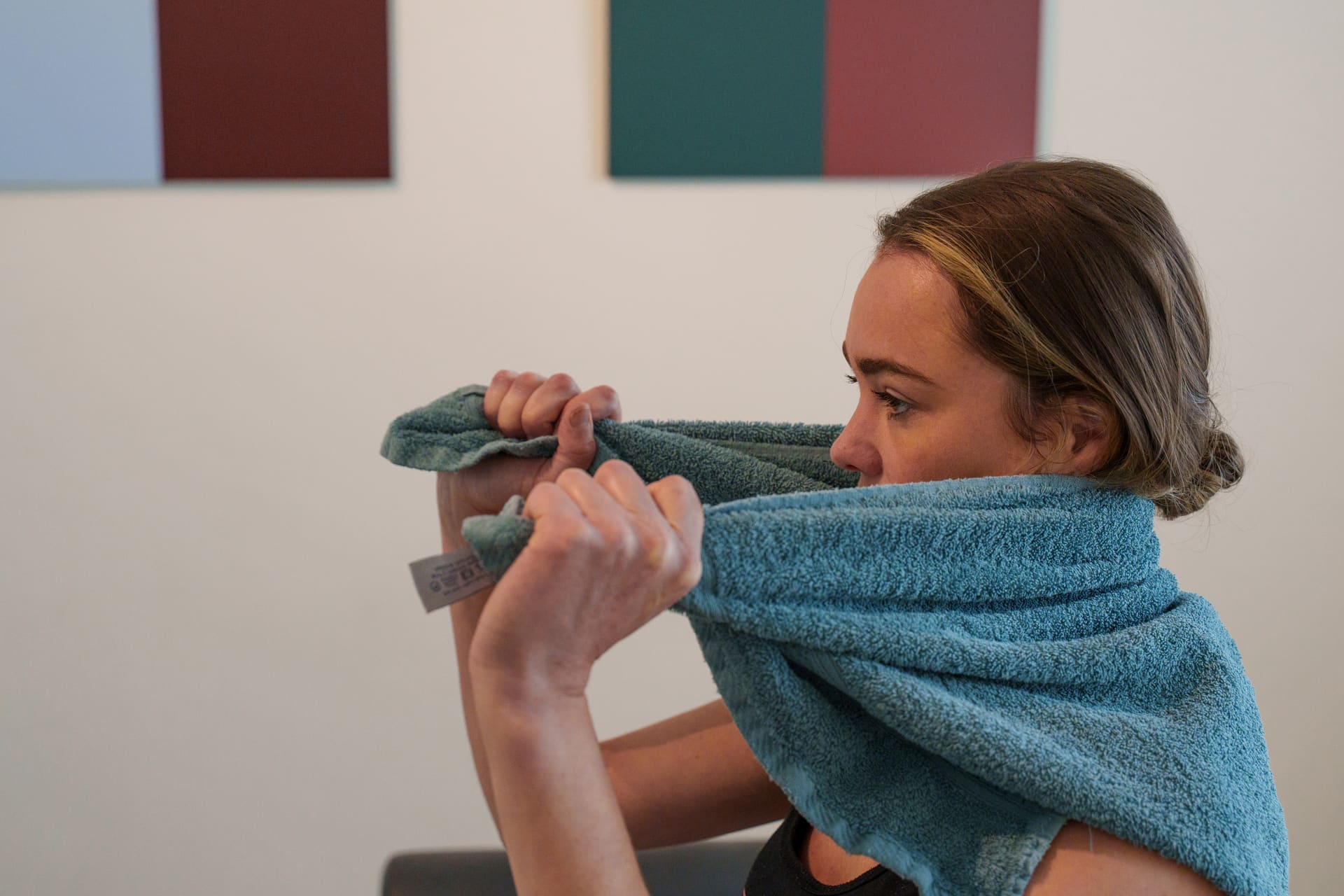 Vrouw rekt haar nek op met een handdoek als zelfoefening tegen hoofdpijn